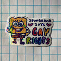 Sticker with SpongeBob SquarePants holding a sign saying 'SpongeBob SAYS GAY RIGHTS' on a grid background