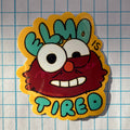 Sticker of a tired cartoon character with 'Elmo is Tired' text on a grid background