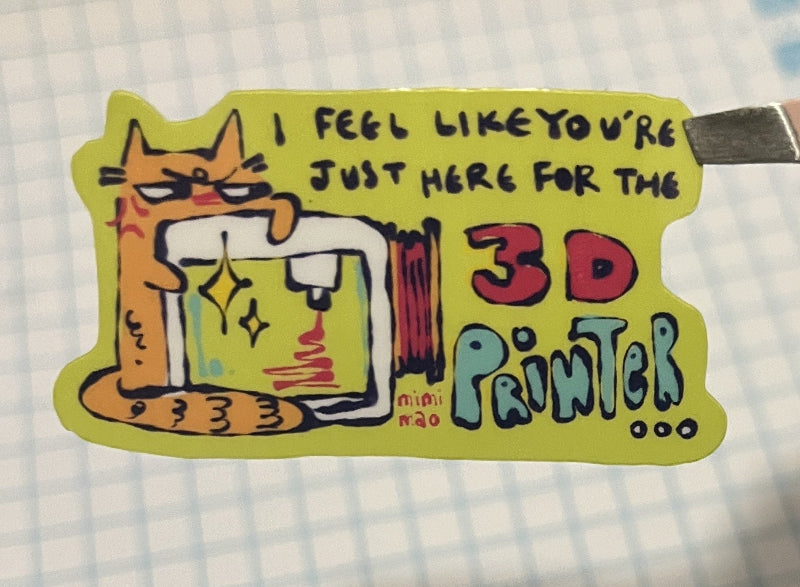 Hand holding a colorful sticker with cartoon cat design on checkered paper